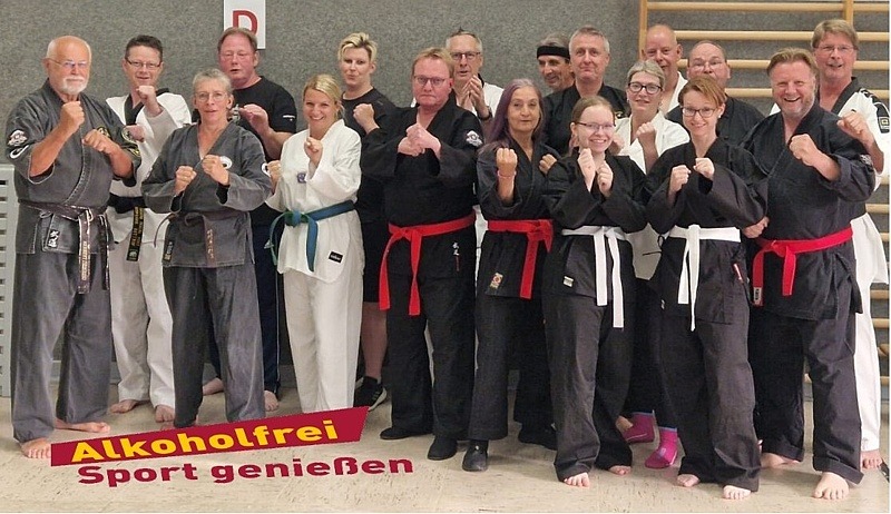 Kampfsportlerinnen und Kampfsportler der Jutsu-Akademie-Harms vor dem Logo "Alkoholfrei Sport genießen" in Kampfstellung