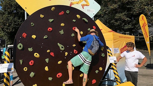 Mann klettert auf einer Veranstaltung auf der Kletterscheibe im „Alkoholfrei Sport genießen“-Eventareal