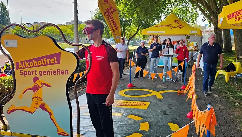 Ein junger Mann läuft mit einer Rauschbrille über den Rauschbrillenparcours von „Alkoholfrei Sport genießen“.