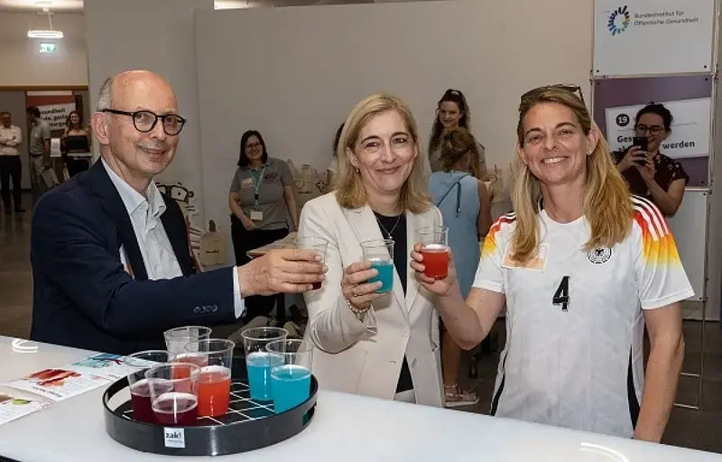 Dr. Johannes Nießen, Bundesgesundheitsministerin Nina Warken und Nia Künzer (von links nach rechts) an der alkoholfreien Cocktailbar im Bundesgesundheitsministerium