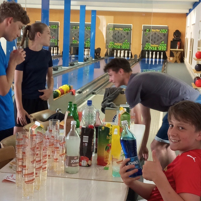 Jugendliche Sportkegler mit alkoholfreien Cocktails an der Kegelbahn.