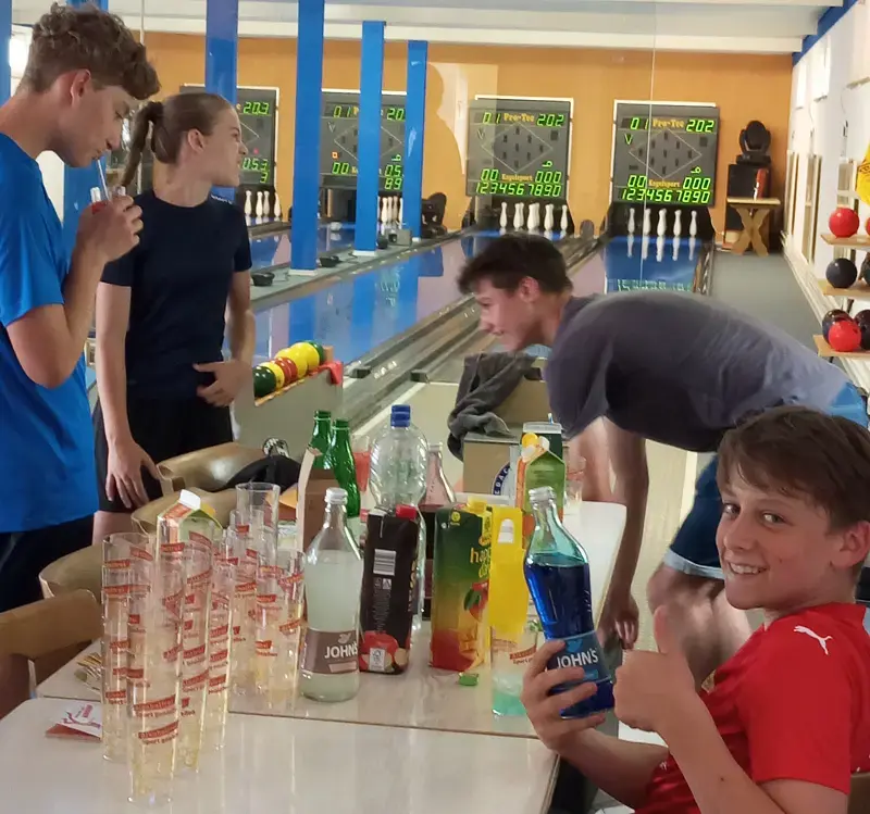 Jugendliche Sportkegler mit alkoholfreien Cocktails an der Kegelbahn.