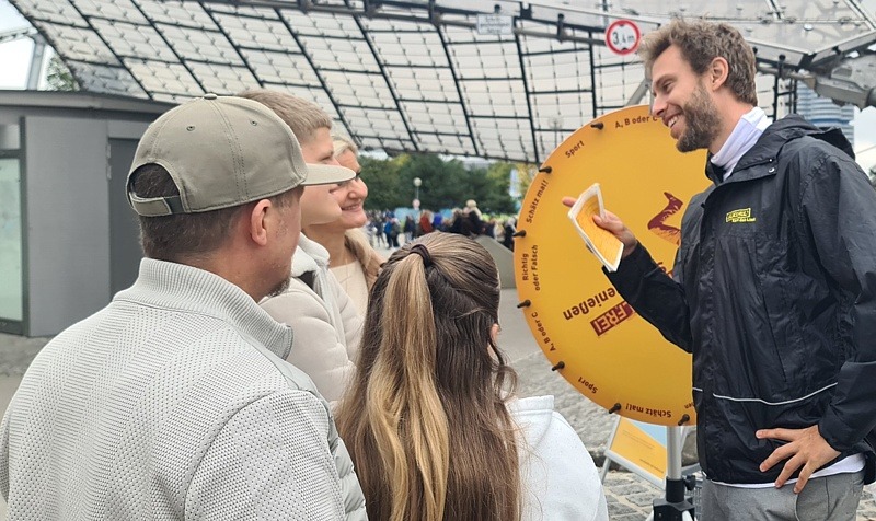Ein Moderator und eine Familie stehen vor einem Glücksrad.