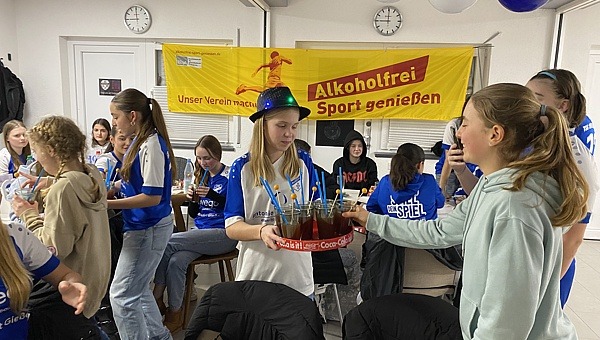 Teenager im Vereinsheim stehen um ein Tablett mit Cocktails.