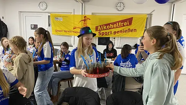 Teenager im Vereinsheim stehen um ein Tablett mit Cocktails.