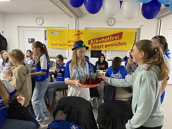 Teenager im Vereinsheim stehen um ein Tablett mit Cocktails.