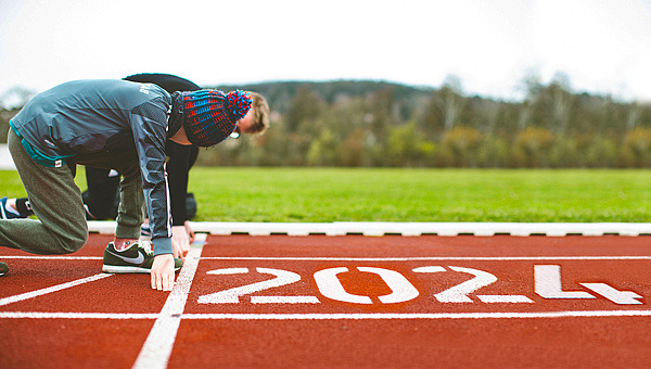 Junge mit Pudelmütze am Start auf roter Außenlaufbahn, auf der 2024 steht.