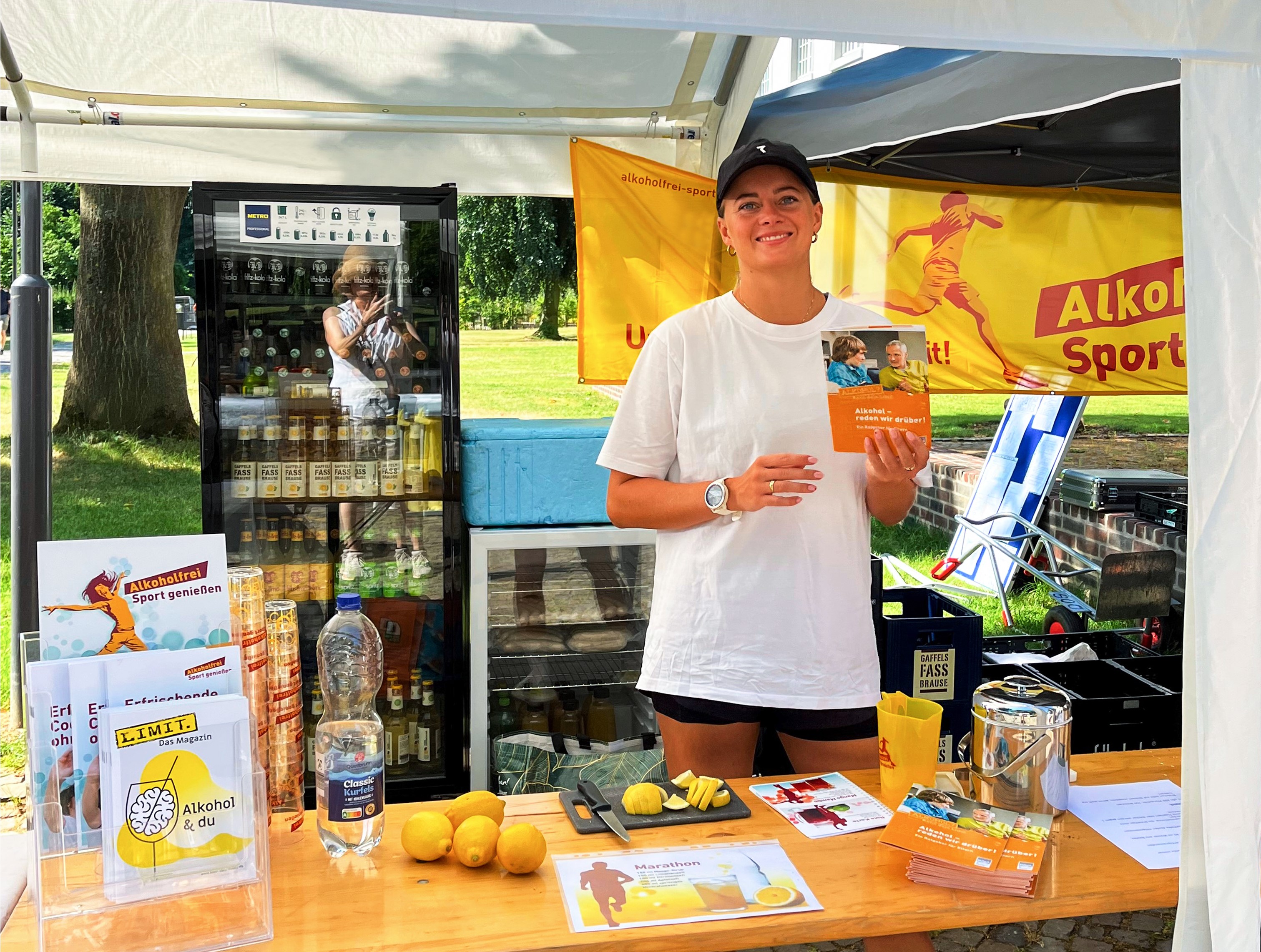 Junge Dame hinter dem einladend gestalteten  „Alkoholfrei Sport genießen“-Infostand.