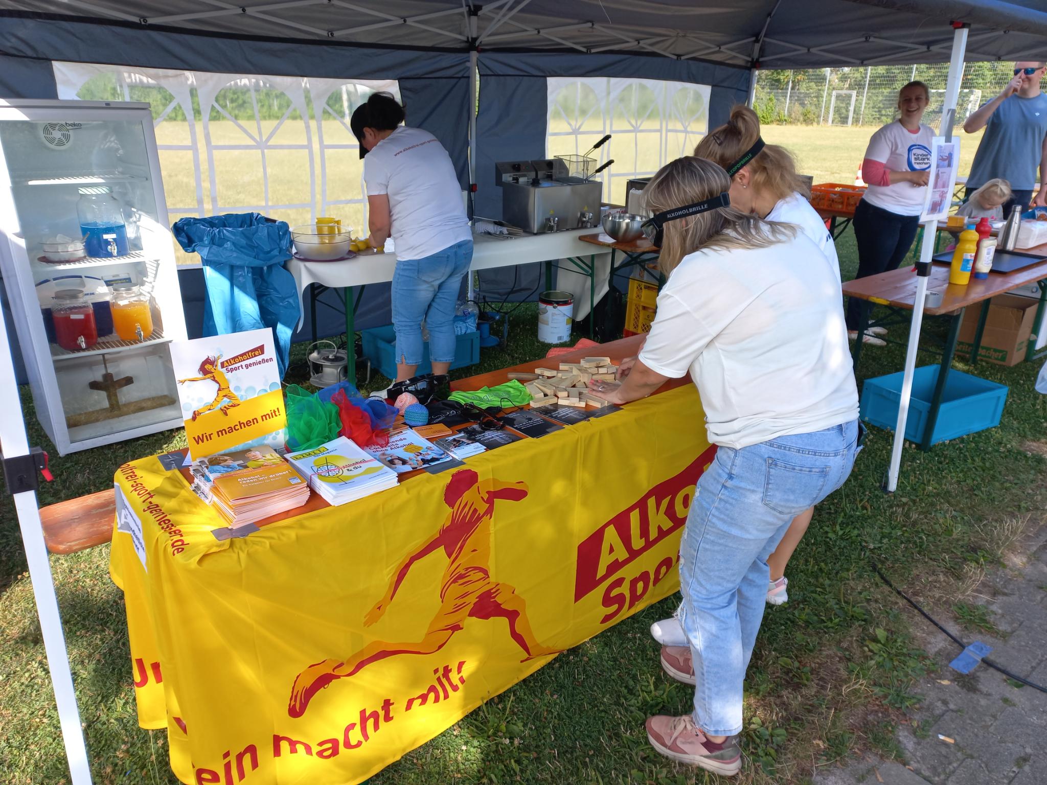 Der Infotand mit „Alkoholfrei Sport genießen“-Aktionsbanner, an dem sich Jugendliche mit Rauschbrille beim Holzklötze-Stapel-Spiel übten.
